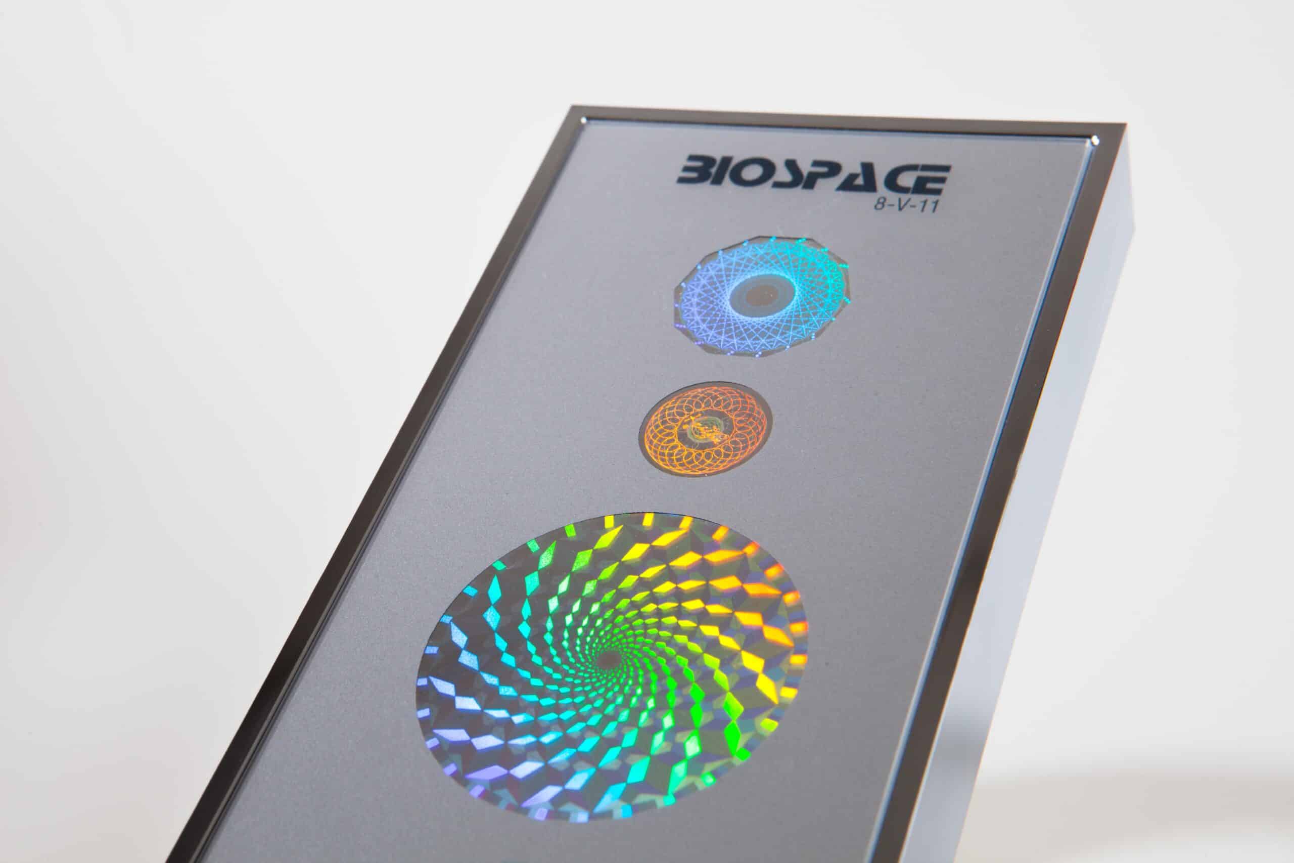 BioSpace 8V11 Diamond featuring three holographic spiral designs in blue, orange, and multicolor on a gray background. The product is housed in a sleek rectangular frame with the brand logo displayed prominently at the top.