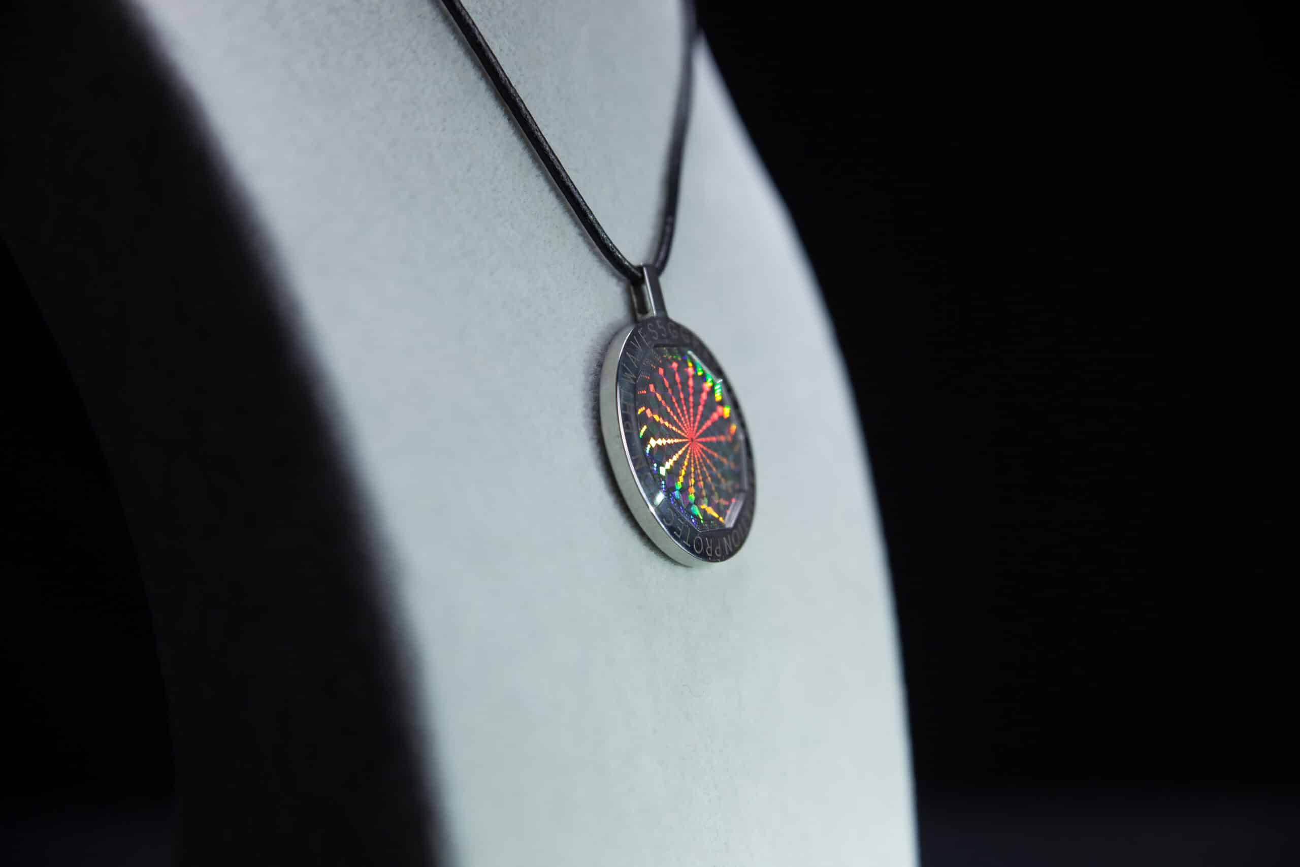 PhiWaves Jewel Diamond pendant necklace featuring a round design with a rainbow-colored diamond cut, displayed on a black cord, set against a gray background that highlights its sparkling details.