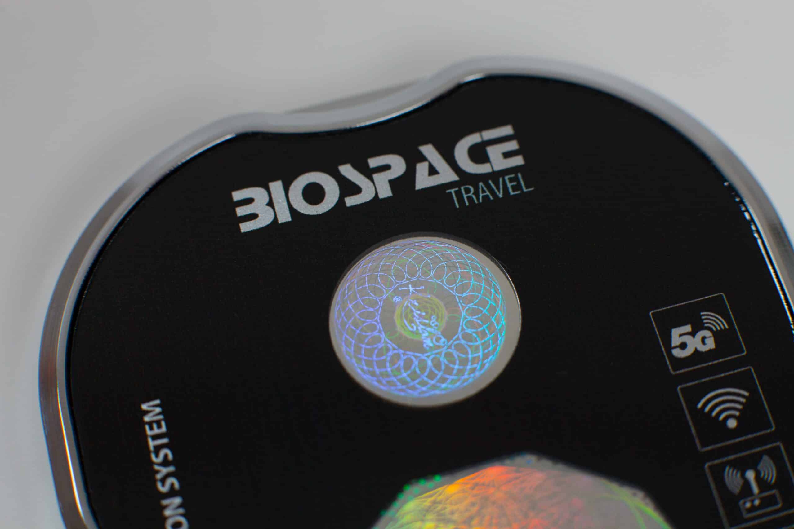 Close-up of the BioSpace Travel Diamond, featuring a black round shape with a holographic circular design. The device includes symbols for WiFi and 5G connectivity, showcasing its modern technology and sleek design.