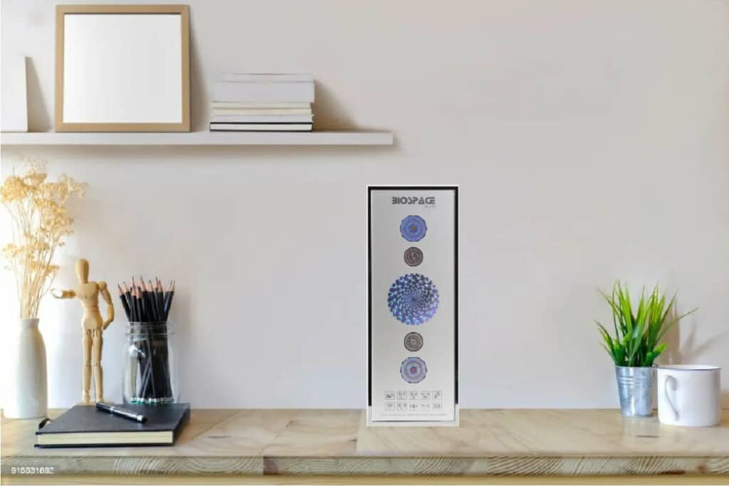 BioSpace 8V11 Diamond wall art displaying circular patterns in blue, gray, and beige colors. The piece is positioned on a minimalist wooden shelf alongside decorative elements like a plant, books, and art supplies.
