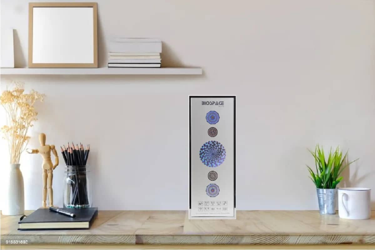 BioSpace 8V11 Diamond wall art displaying circular patterns in blue, gray, and beige colors. The piece is positioned on a minimalist wooden shelf alongside decorative elements like a plant, books, and art supplies.